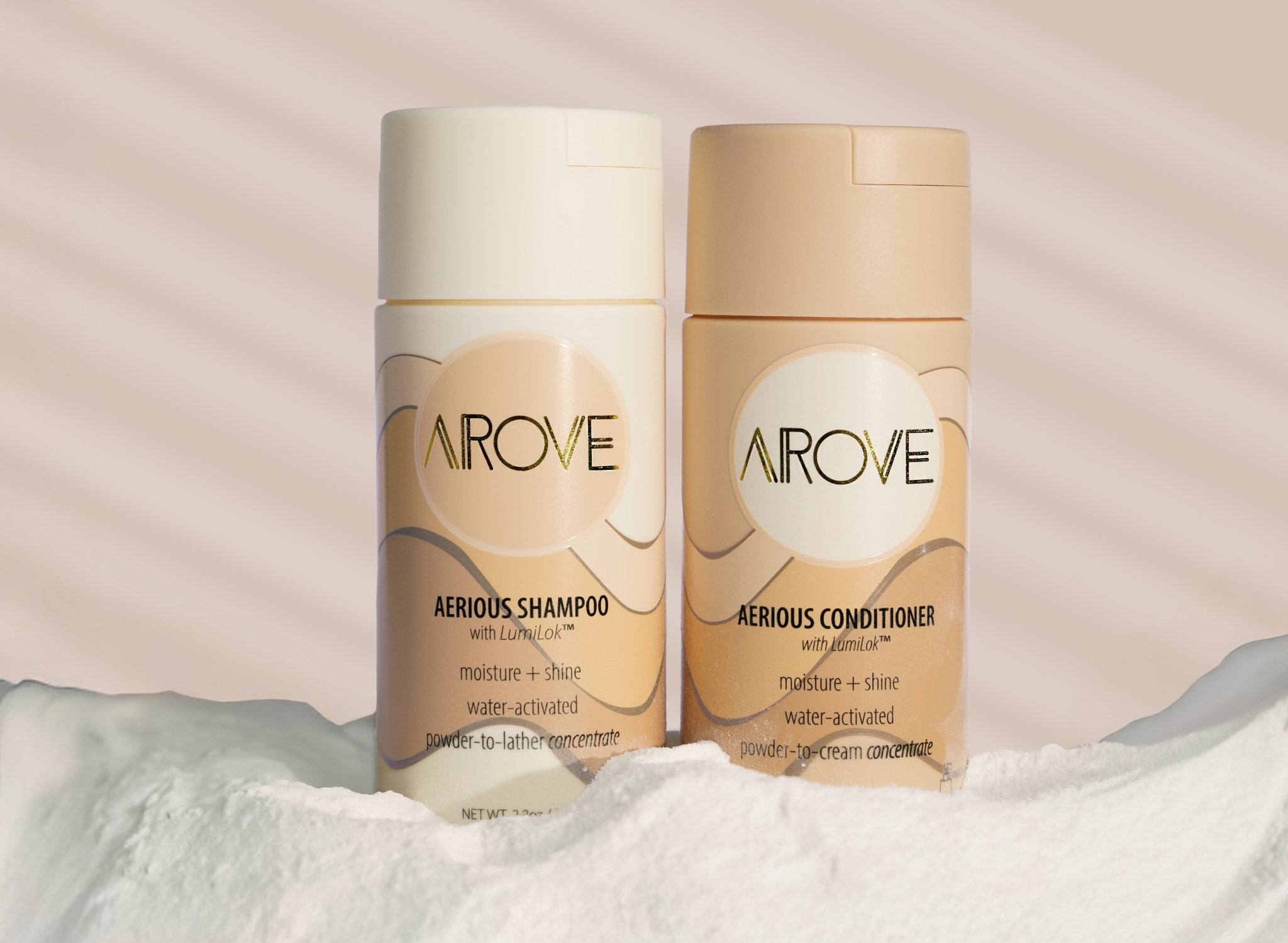 Arove Beauty Aerious Shampoo and Aerious Conditioner bottles standing in soft powder with gentle sunlight, showcasing water-activated powder haircare for moisture, shine, and sustainability.