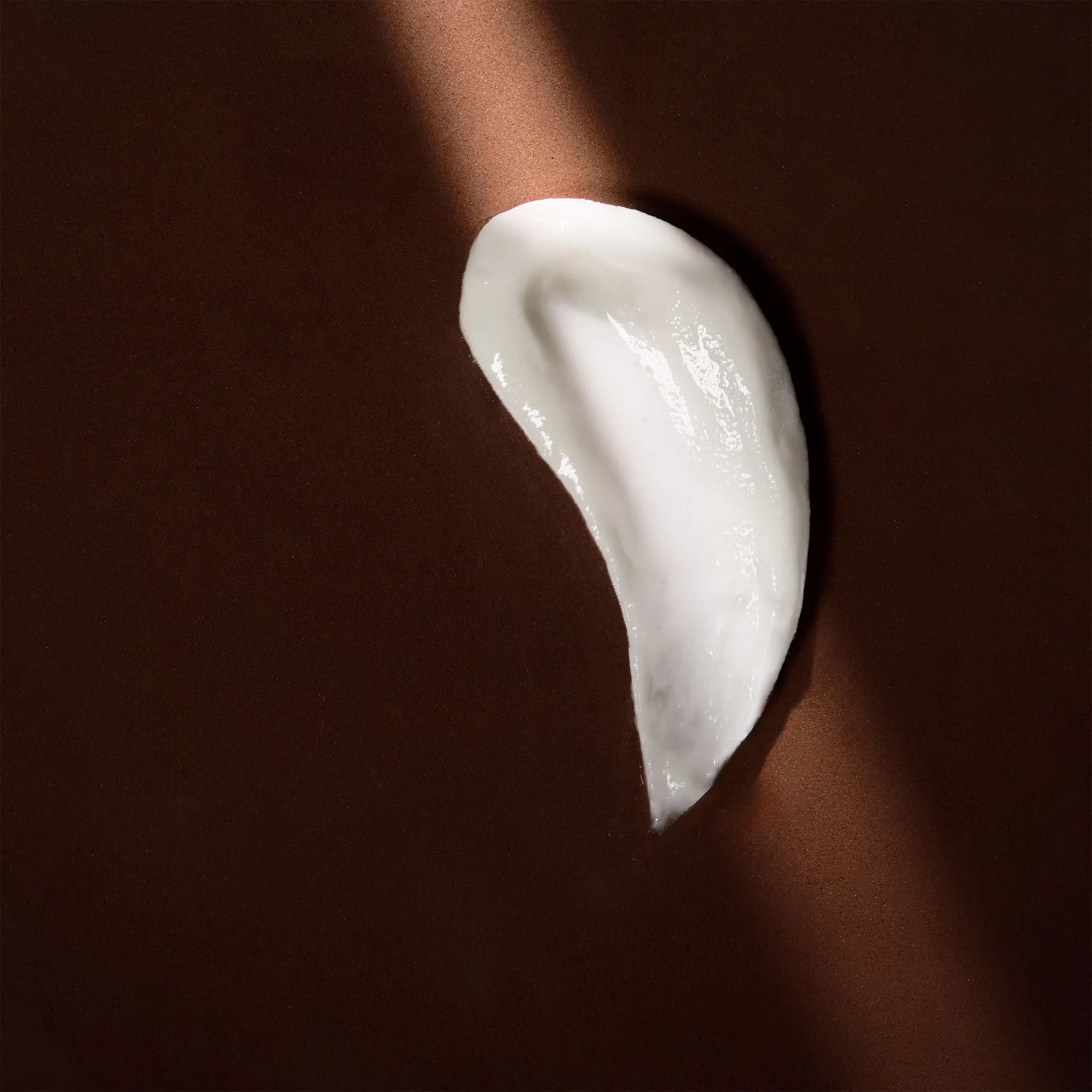 Arove Aerious Conditioner swatch—creamy white hair conditioner texture on a dark brown background