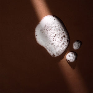 Arove Aerious Shampoo—soft foamy lather with bubbles on a dark brown background
